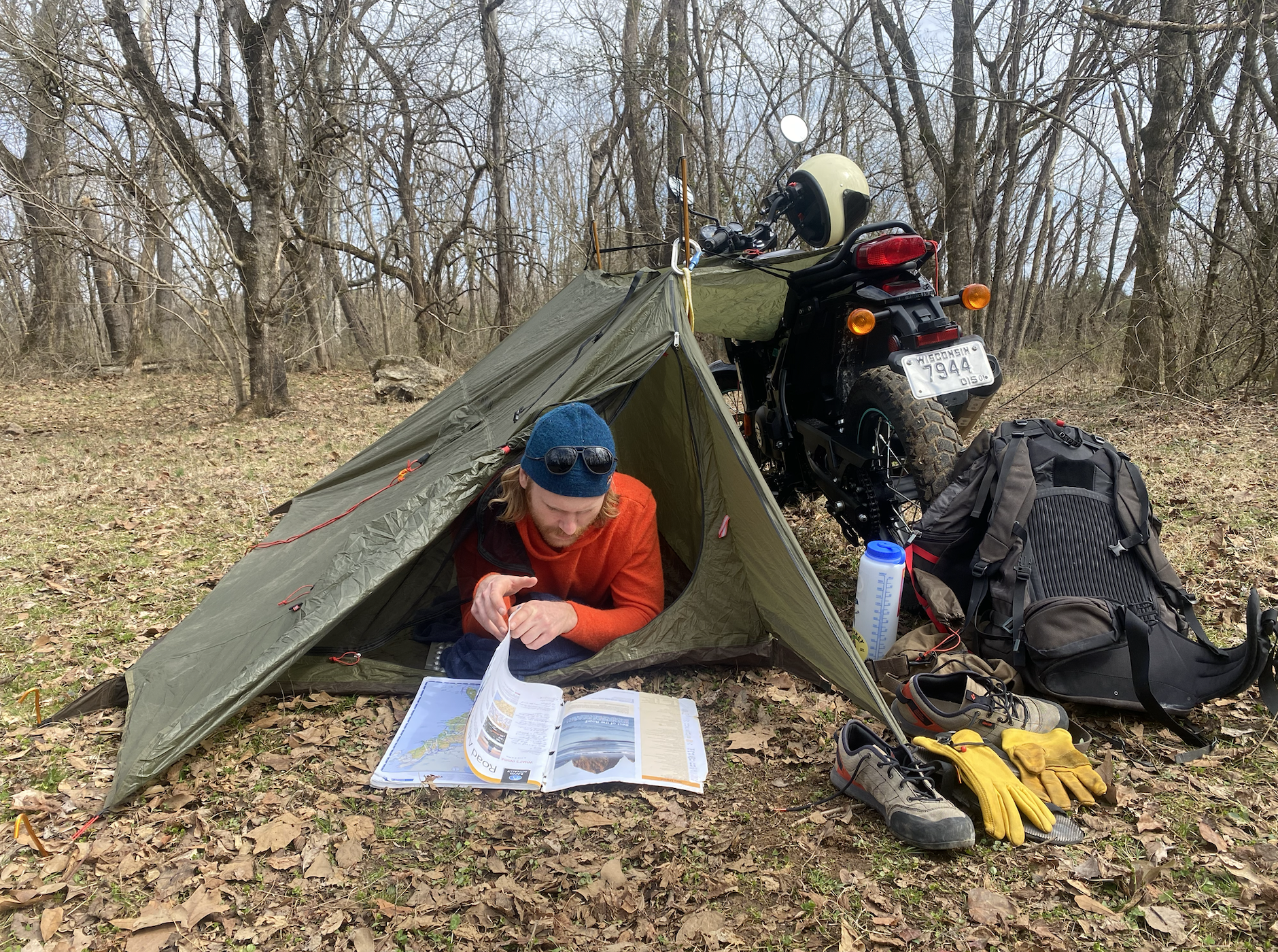 a man in a tent pitched next to a motorcycle