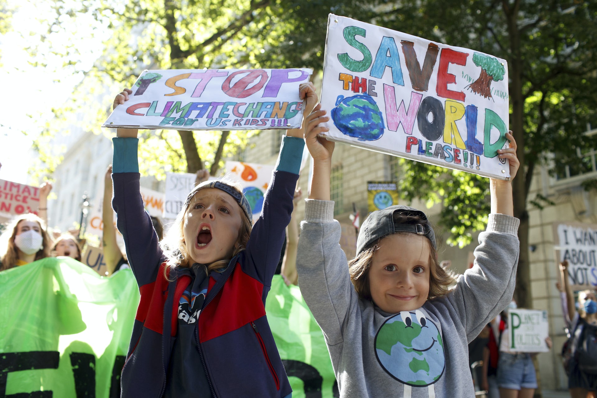 two children hold signs reading 'save the world'