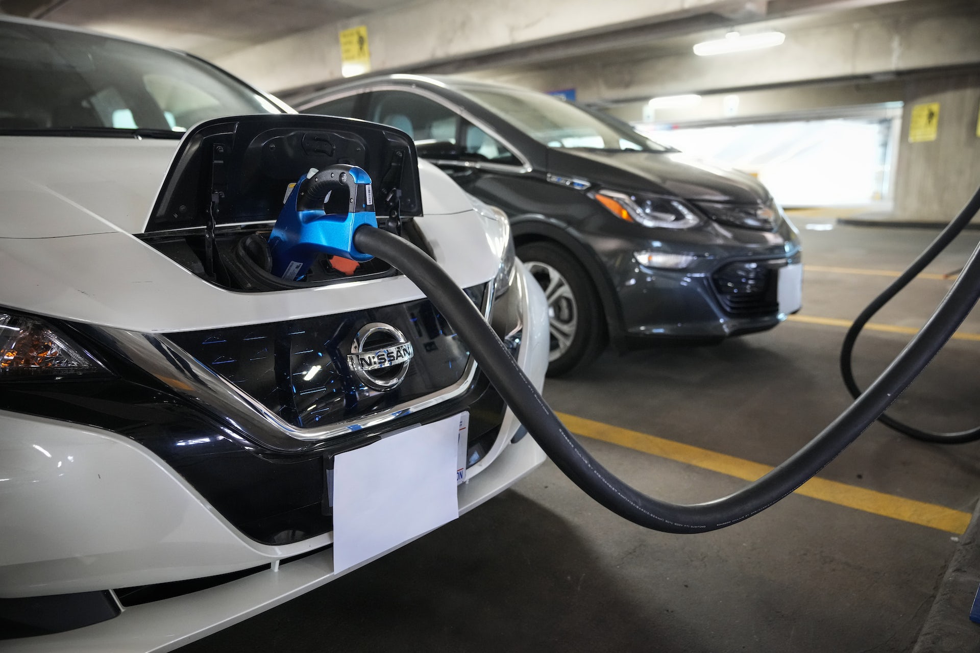 A Nissan Leaf EV charges in a parking garage.