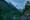 a kayaker paddles in a misty mountain lake, dense forests on all sides