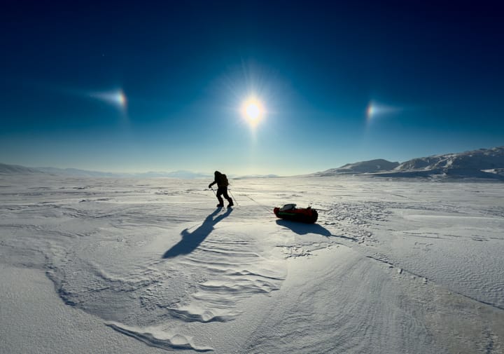 a man pulling a sled across a frozen tundra