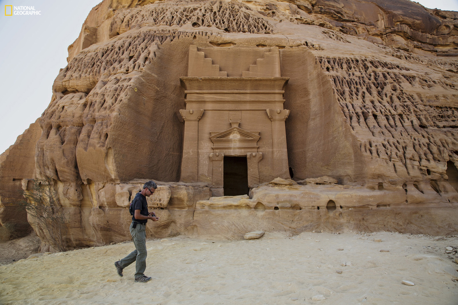 Paul Salopek wanders through the ancient Nabataean ruins of Madain Salih, carved into sandstone outcrops some 2,000 years ago. These structures were used as tombs for the wealthy during the Nabataean era. The kingdom stretched from its capital Petra in Jordan south to Madain Salih in the Hejaz region of present-day Saudi Arabia. Photo shows a tomb façade in the Al Khuraymat area of Madain Salih. Join the journey at outofedenwalk.org.Photograph by John Stanmeyer / National Geographic