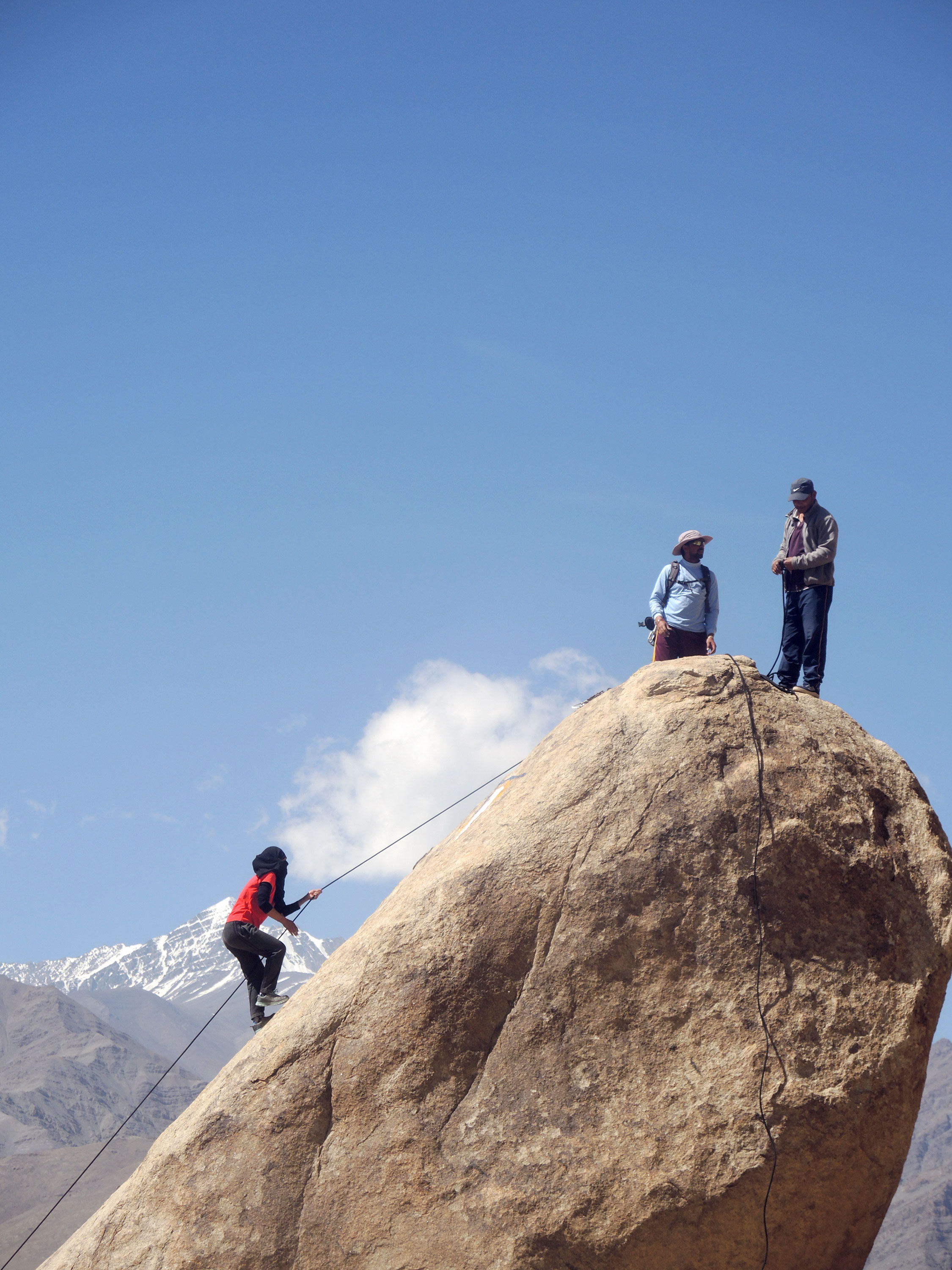 Instructor La Do Tsering makes her way up a rock in the foreground of the Stok Kangri. 