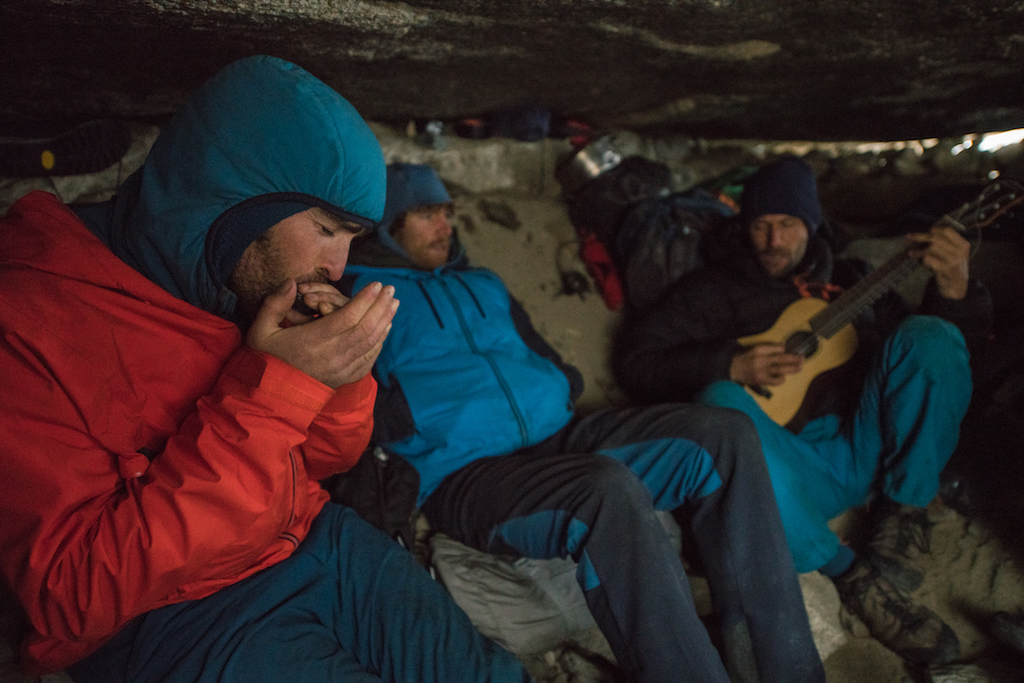 Sean Villanueva, Nico Favresse and Seibe Vanhee play music to pas the time while waiting out a storm in the Belgium bivy cave near the base of the Torres. Torres del Paine, Patagonia, Chile.
