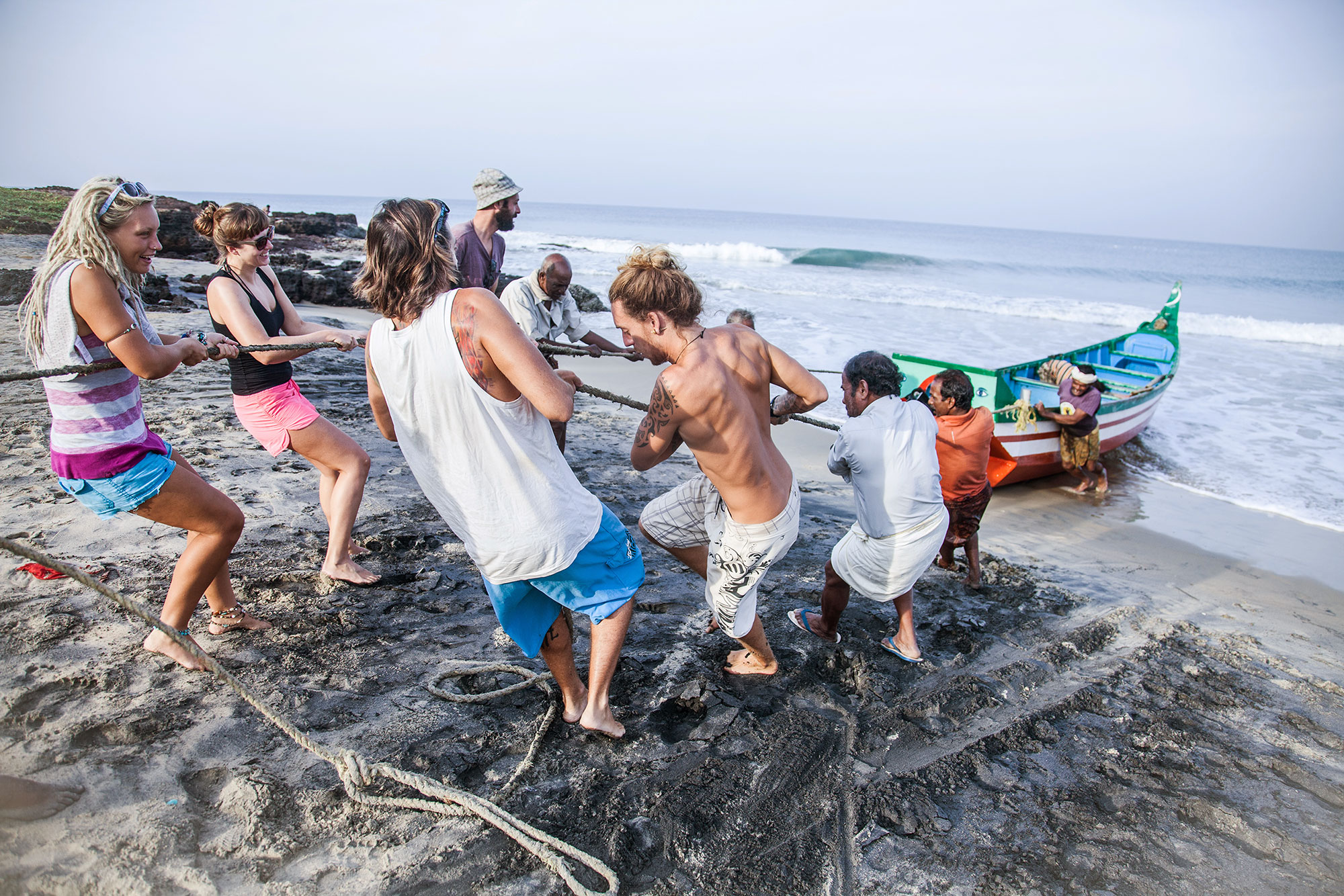Surfers help fishermen drag their boat to the shore. PHOTO: Berta Tilmante